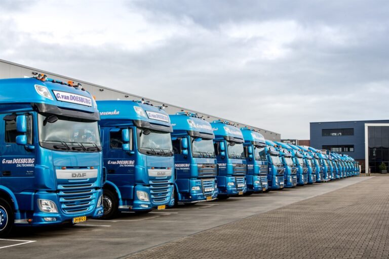 Een lange rij blauwe GD-iTS-vrachtwagens naast elkaar op het terrein