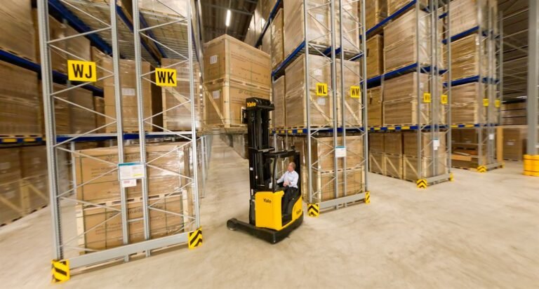 Medewerker op een reachtruck tussen hoge magazijnstellingen met pallets